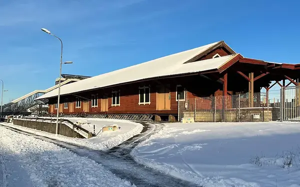 Röd avlång träbyggnad i snöigt vinterlandskap. Byggnaden heter Godsmagasinet