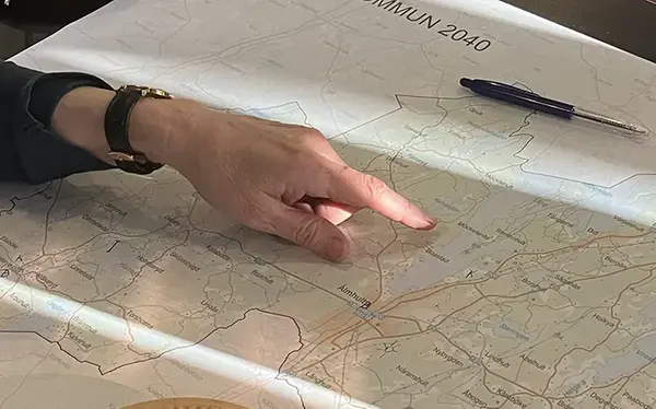 En hand om pekar på en karta över Älmhult