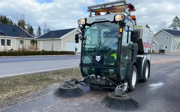 Lien traktor med borstar fram som tar upp gruset.