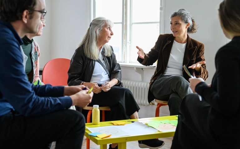 En grupp människor som sitter runt ett bord och pratar.