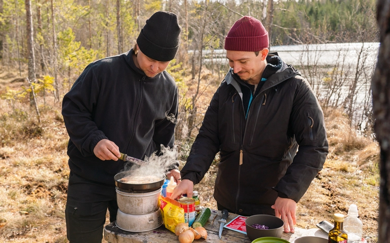 Två personer lagar mat i naturen