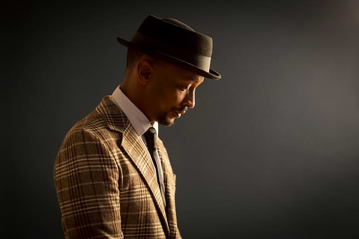 Profilbild på Daniel Lemma klädd i brun hatt och brun/beige kavaj och slips