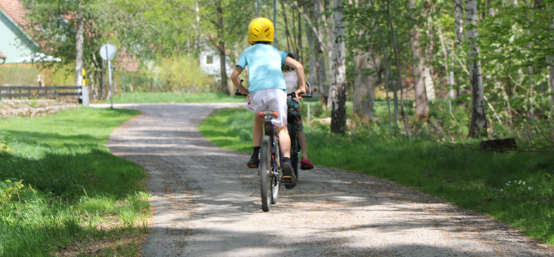 Två barn cyklar på en cykelväg med natur runt om