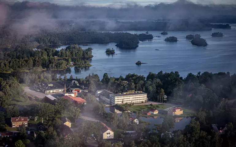 Flygfoto över Diö, en gammalfabrik några hus och sjön Möckeln med öar.