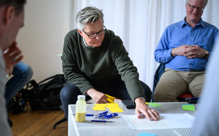 Lars Persson, näringslivschef i Älmhults kommun, sitter med en grupp runt ett bord och pekar på ett papper.