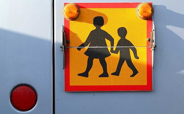 Skolbussskylten: två barn som håller hand