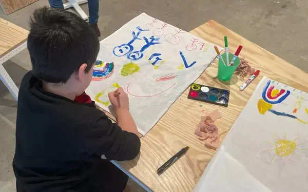 Barn sitter och målar med pensel och färg