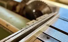Närbild på en silvrig sågmaskin som används i en snickerifabrik
