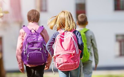 Barn med ryggsäckar går mot skolan